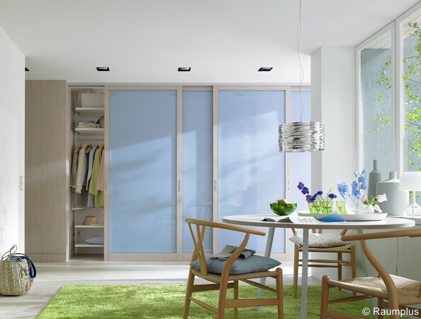 Helles, modernes Esszimmer mit Schiebetürenschrank, Esstisch und Holzstühlen.
