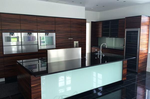 Moderne Designerküche mit Kochinsel, dunklen Holzfronten und hochwertigen Einbaugeräten.