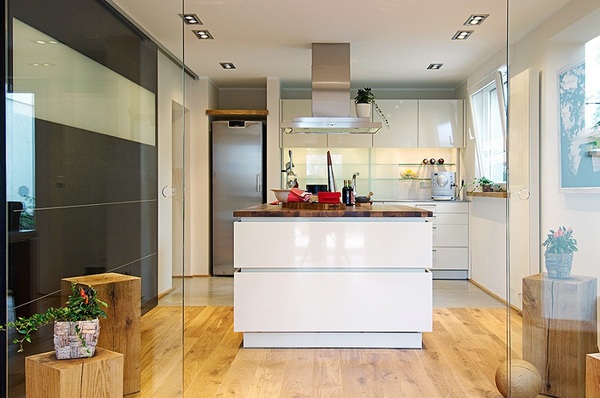 Moderne helle Küche mit Kochinsel, Holzfußboden und großen Fenstern für viel Tageslicht.